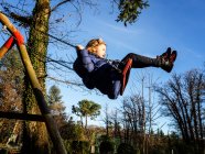 Chica balanceándose en un columpio en un parque infantil, Italia - foto de stock