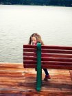 Вид сзади на девушку, сидящую на скамейке, оглядывающуюся через плечо, Польша — стоковое фото
