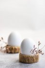 Два вареных яйца в яичных чашках рядом с сушеными цветами — стоковое фото