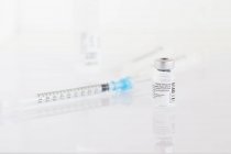 Un flacon du vaccin contre le coronavirus et une seringue sur une table dans une clinique — Photo de stock