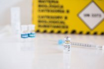 Um frasco para injetáveis da vacina contra o Coronavirus e seringa numa mesa de uma clínica — Fotografia de Stock