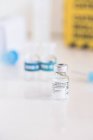 Флакон с вакциной от коронавируса и шприцем на столе в клинике — стоковое фото
