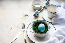 Lugar de Pascua con un huevo de Pascua, flores y una pluma - foto de stock