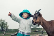 Girl standing next to a goat pointing, Poland — Stock Photo