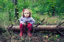 Menina sentada em um tronco de árvore caído na floresta, Polônia — Fotografia de Stock