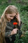 Retrato de una niña de pie en un campo sosteniendo una amapola, Rusia - foto de stock