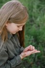 Porträt eines Mädchens, das ein Insekt in ihrer Hand betrachtet, Russland — Stockfoto