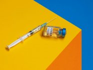 Ковид-19 вакцина и шприц на столе — стоковое фото