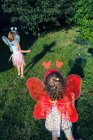 Две девушки в сказочных крыльях играют в саду — стоковое фото