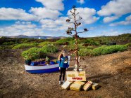 Девушка, стоящая рядом с елкой, украшенной рождественскими украшениями в сельской местности, Лансароте, Канарские острова, Испания — стоковое фото