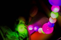 Girl lying in bed sleeping under multi coloured lights — Stock Photo