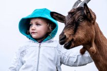 Portrait of a girl stroking a goat, Poland — Stock Photo