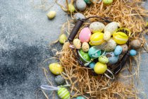 Multi ovos de Páscoa coloridos em uma cesta cercada com palha — Fotografia de Stock