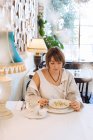 Woman sitting in a restaurant eating dumplings — Stock Photo