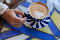 Frau sitzt an einem Tisch und genießt eine Tasse Kaffee — Stockfoto