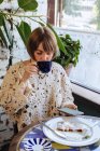 Donna seduta in un caffè a bere caffè e a guardare il suo telefono cellulare — Foto stock