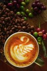 Vista aérea de um cappuccino com grãos de café crus e torrados — Fotografia de Stock