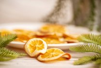 Teller mit getrockneten Orangen auf einem Tisch mit Tannenzweigen zu Weihnachten — Stockfoto