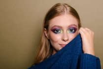 Porträt einer schönen Frau mit auffälligem Augen-Make-up, die ihren Pullover über ihr Gesicht zieht — Stockfoto
