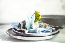 Easter place setting with stone plates and blue colored holiday decoration — Stock Photo