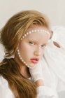 Retrato de una hermosa chica con perlas en la cara - foto de stock
