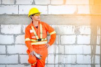 Portrait of a construction worker in reflective clothing leaning against a wall, Thailand — Stock Photo