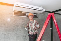 Técnico instalando una unidad de aire acondicionado en una pared, Tailandia - foto de stock