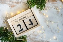 Calendario in blocchi di legno per la vigilia di Natale con luci di fata e rami di abete — Foto stock