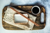Coloque el ajuste para la cena con comida asiática con tazón y palillos sobre fondo rústico - foto de stock