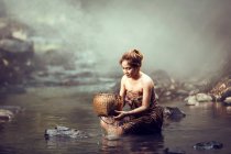 Donna seduta in un fiume a fare il bagno, Thailandia — Foto stock