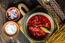 Traditionelle ukrainische Rote-Bete-Suppe Red Borscht serviert in einer Schüssel auf rustikalem Tisch — Stockfoto