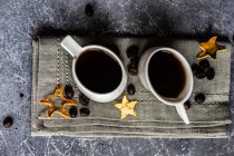 Tasses en céramique blanche avec boisson chaude au café sur fond textile gris — Photo de stock