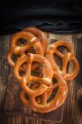 Pilha de pretzels recém-assados em uma tábua de corte de madeira — Fotografia de Stock