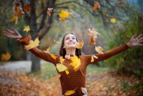 Porträt eines lächelnden Mädchens, das Herbstblätter in die Luft wirft, Bulgarien — Stockfoto