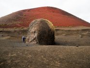Fille debout près d'un rocher géant levant les yeux, Lanzarote, Îles Canaries, Espagne — Photo de stock