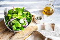 Healthy green salad concept with iceberg salad leaves, cucumber, sesame oil and seeds served in a bowl — Stock Photo