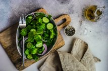 Концепція здорового зеленого салату з листям салату айсберг, огірком, кунжутною олією та насінням, поданими в мисці — стокове фото