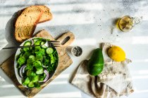 Gesundes grünes Salatkonzept mit Eisbergsalatblättern, Gurke, Sesamöl und Samen in einer Schüssel — Stockfoto