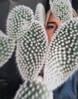 Женщина смотрит сквозь кактус — стоковое фото
