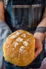 Frau hält einen Laib frisch gebackenes Brot in der Hand — Stockfoto