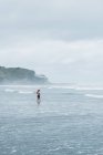 Mujer de pie en el océano surf, Mangawhai Heads, Northland, Isla Norte, Nueva Zelanda - foto de stock