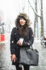 Retrato de una mujer sonriente en una parka forrada de piel de pie en la nieve, Itaewon, Corea del Sur - foto de stock