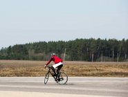 Homme faisant du vélo le long d'une route vide, Lituanie — Photo de stock