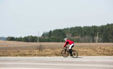 Homme faisant du vélo le long d'une route vide, Lituanie — Photo de stock
