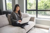 Woman sitting on a sofa working from home — Stock Photo