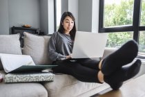 Frau sitzt auf Sofa und arbeitet von zu Hause aus — Stockfoto