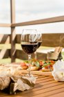 Antipasto e vinho tinto em uma mesa ao ar livre — Fotografia de Stock