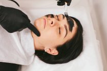 Косметолог готує жінку до лікування вуглецевої шкірки в клініці — стокове фото
