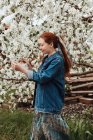 Lächelnde Frau berührt Blumen an einem Kirschblütenbaum — Stockfoto