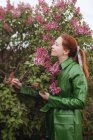 Frau steht draußen und riecht Blumen — Stockfoto
